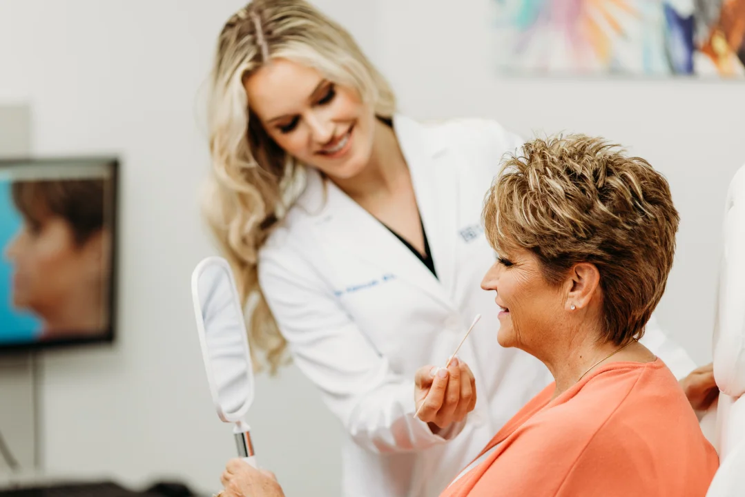 best age for a facelift: woman looking at her facelift results in the mirror