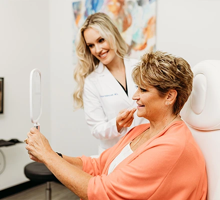 dr-klimczak-with-female-patient-looking-in-the-mirror-at-jowls-treatment-results