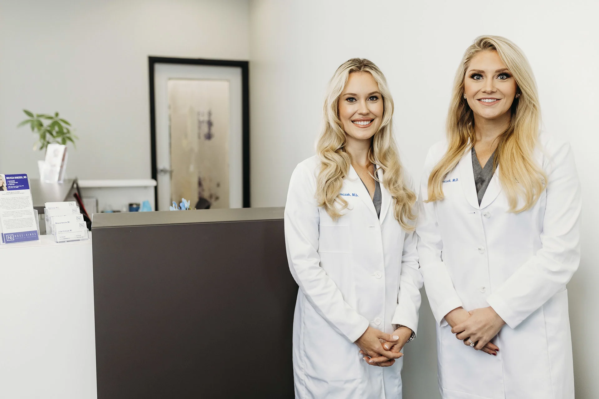Upper face surgery: Two female surgeons smiling in clinic reception area